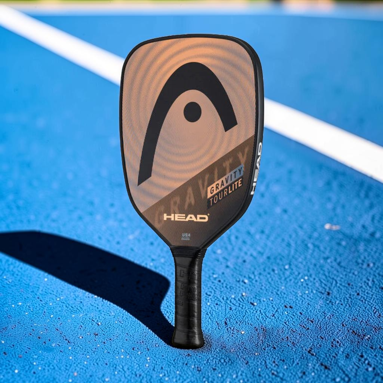 padelpickleball.store HEAD Gravity Tourlite pickleball paddle in orange and black on a green and blue court surface