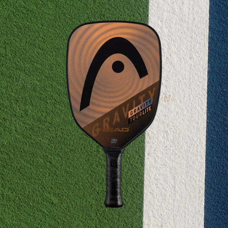 padelpickleball.store HEAD Gravity Tourlite pickleball paddle in orange and black on a green and blue court surface